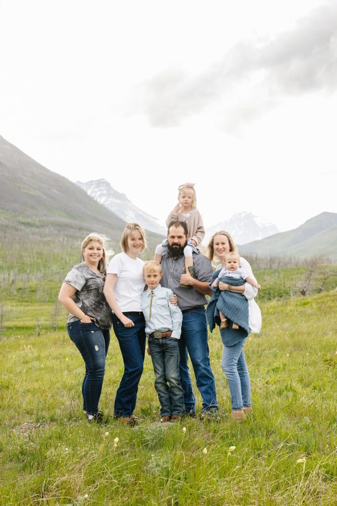 Family standing in grass with mountains in the background