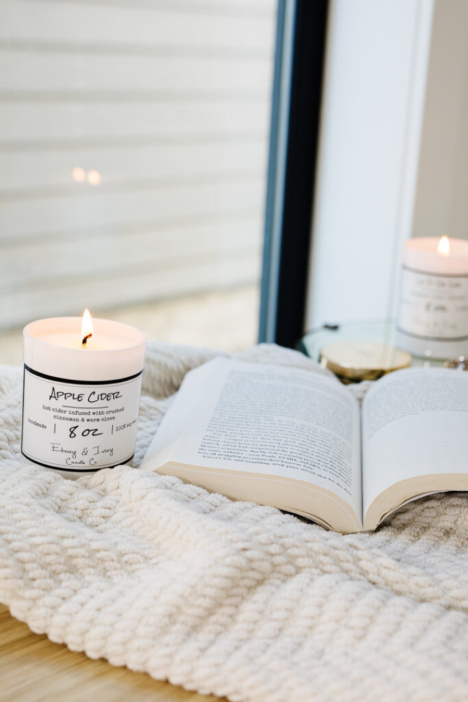 Relaxing scene by a window with Ebony & Ivory Co candles and an open book