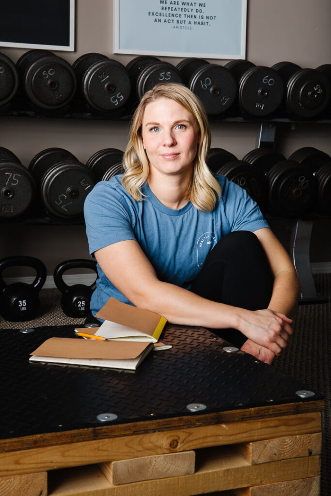 Health coach sitting next to rack of weights