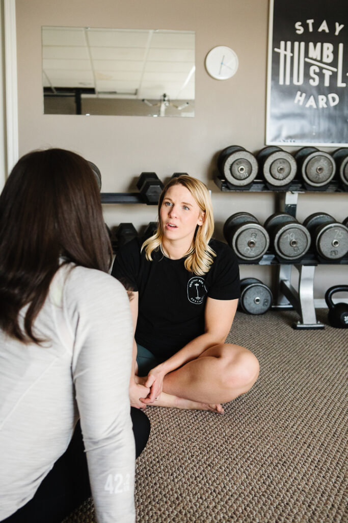 Health and fitness coach instructing client with a diagram on a whiteboard