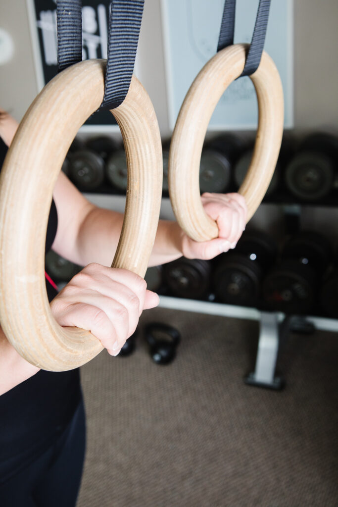 Hands holding rings in a home workout gym. Brand photography session for Healthy Roots Coaching.