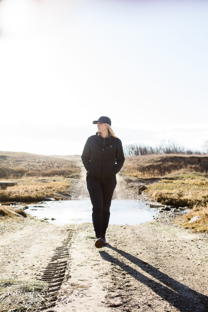 Woman walking on a muddy road past a creek. Health coach brand photography with Esther Beazer of Healthy Roots Coaching. Photographed by Kinsey Holt.