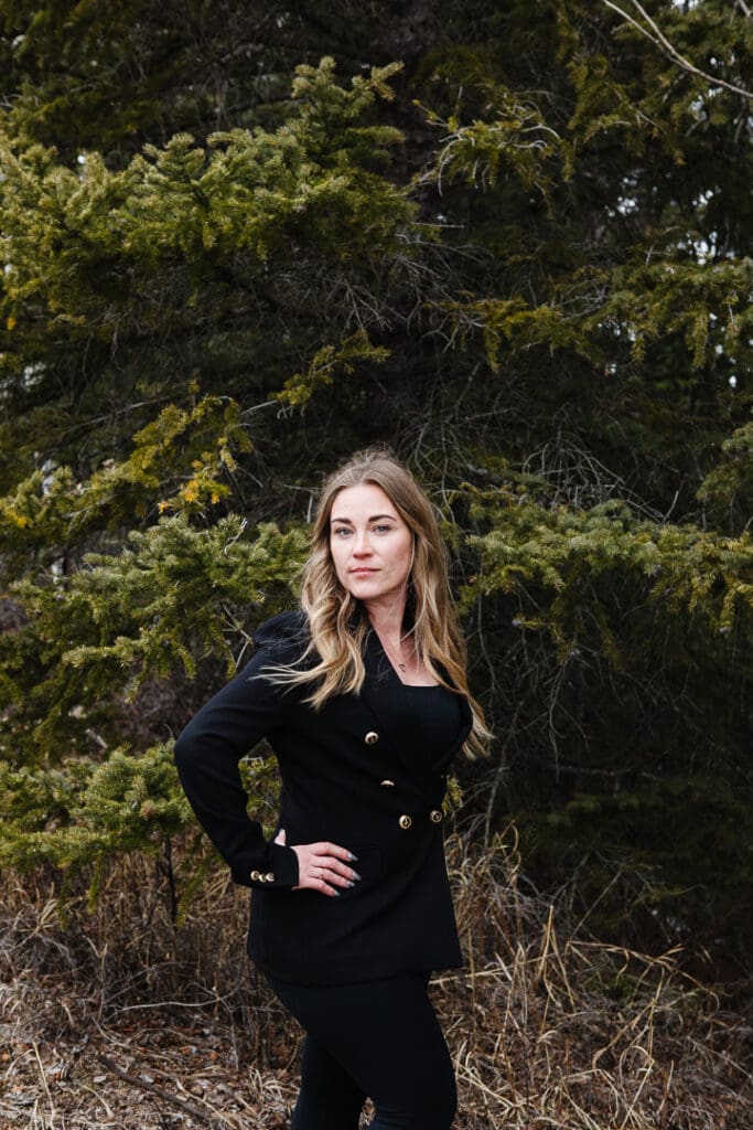 Woman standing in front of spruce trees in the mountains. Brand photo session for a realtor.