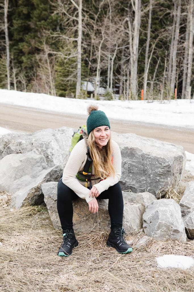 Woman in hiking gear sitting on rock.