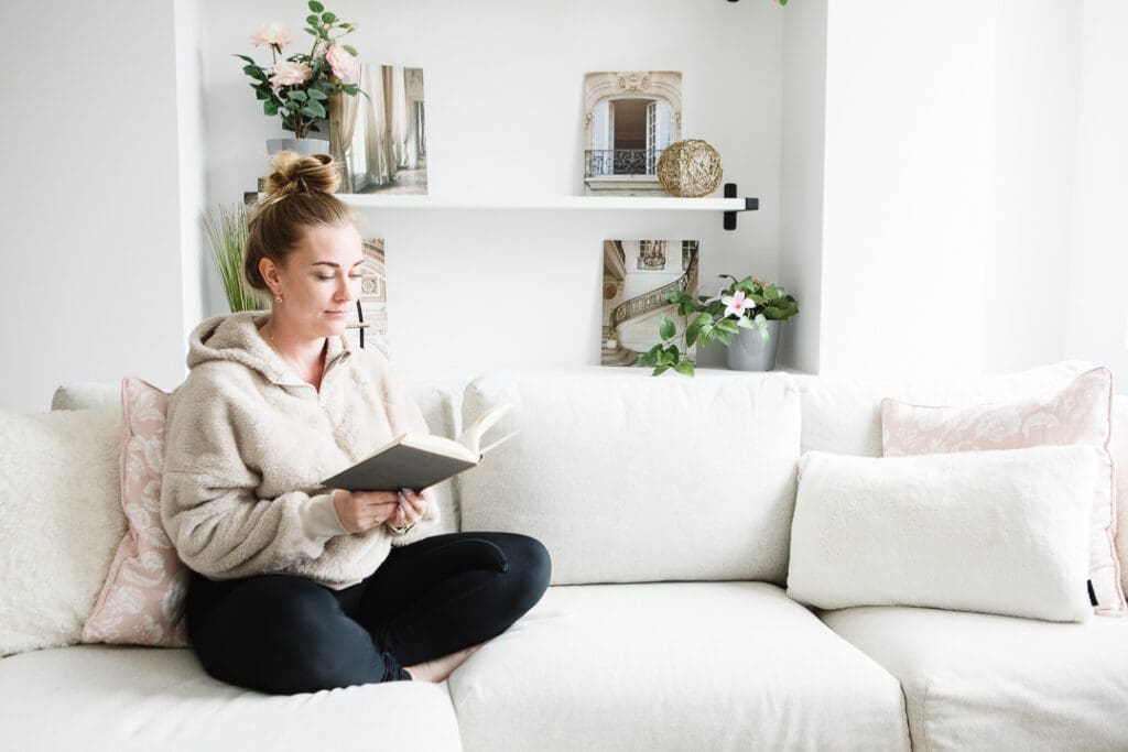 Woman sitting on couch with a book. Crowsnest Pass realtor brand photos.