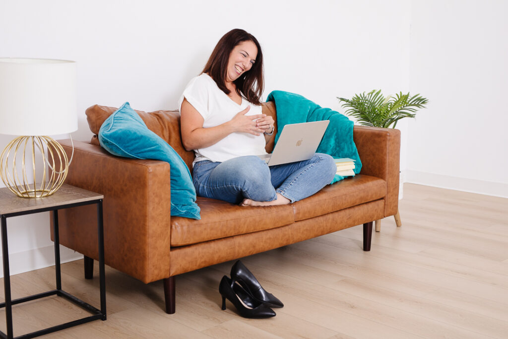 Virtual assistant sitting on couch talking to a client through her laptop screen.