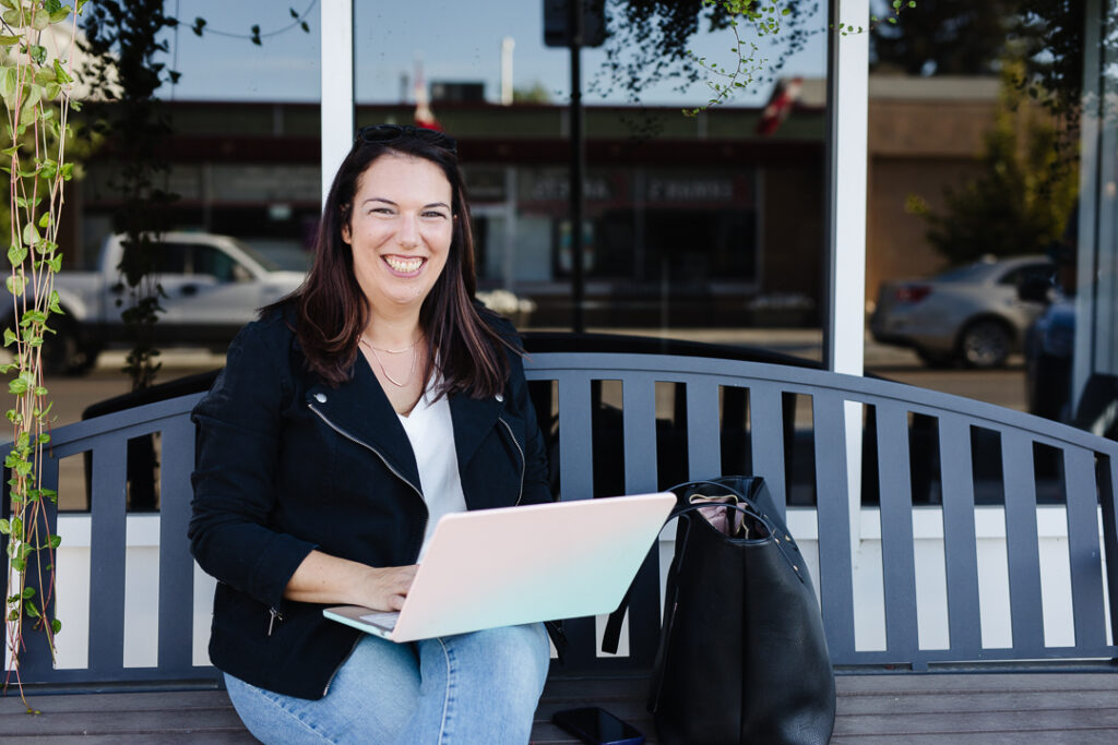 Virtual assistant working on bench in front of local business.